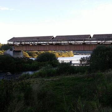 Brücke mit Dachkonstruktion die über einen Fluss reicht